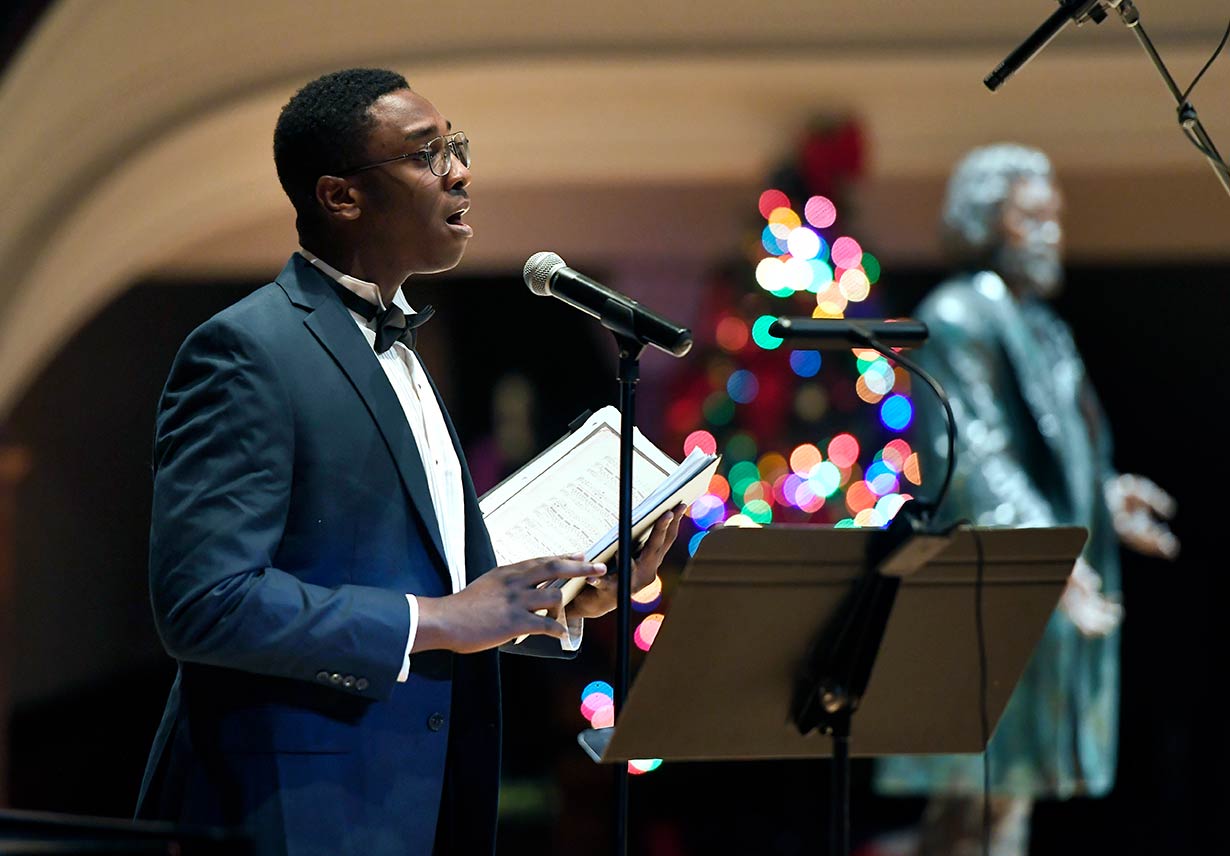 A person in a suit giving a speech from behind a podium.